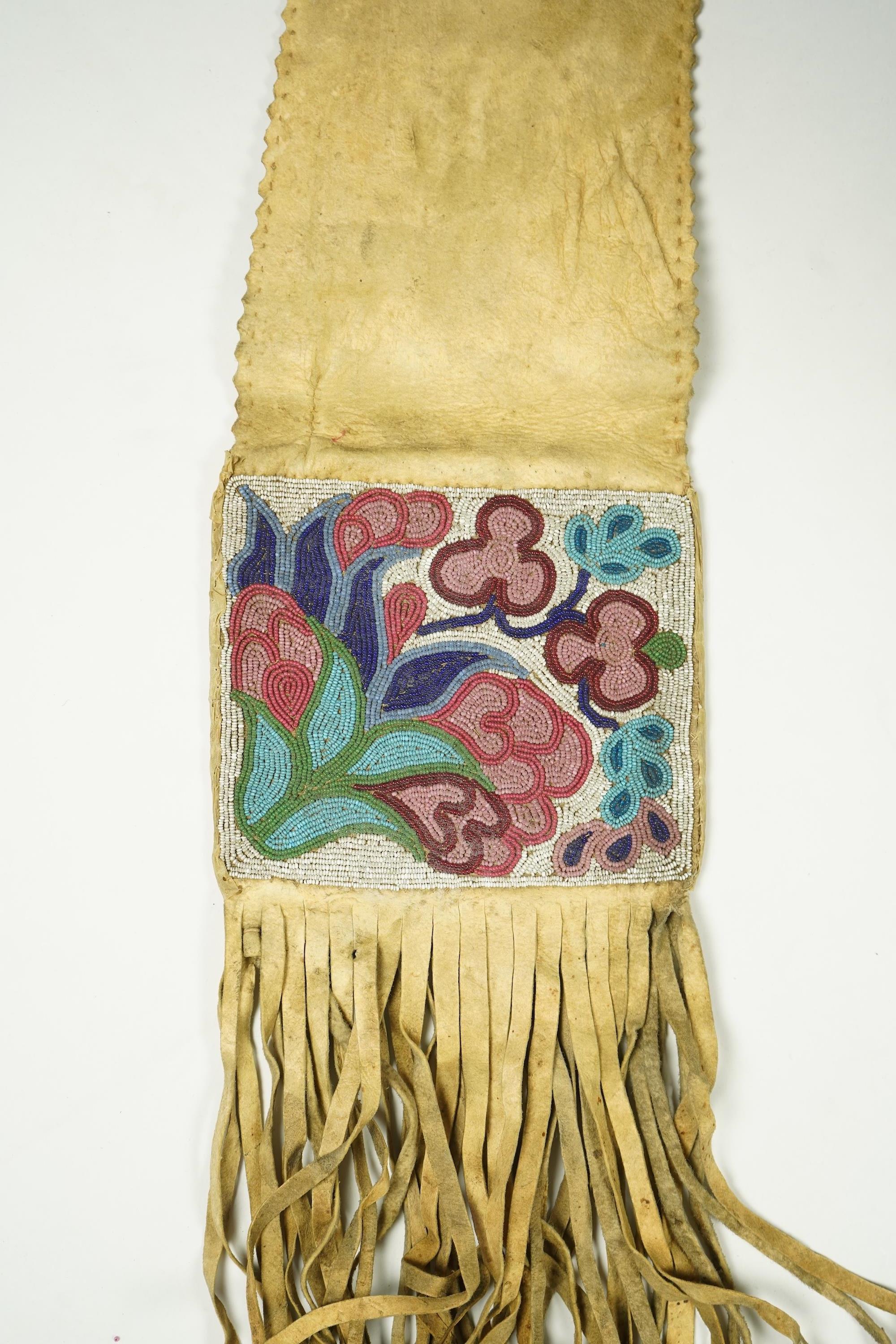 A late 19th century Native American beaded and fringed hide bag. With two different decorative beaded panels front and back. Possibly Cree. 60cm long. Condition - both panels of beadwork are in good condition. The hide a